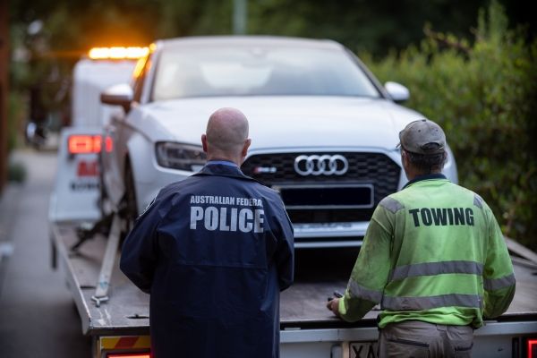 Police officer and tow truck operator confiscating a vehicle