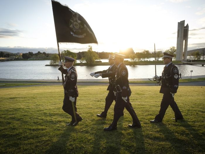 Four AFP members marching with an AFP flag on National Police Remembrance Day