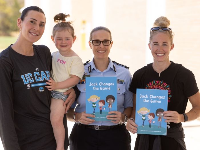 Uniformed police officer with two members of the public holding a child prevention fiction book